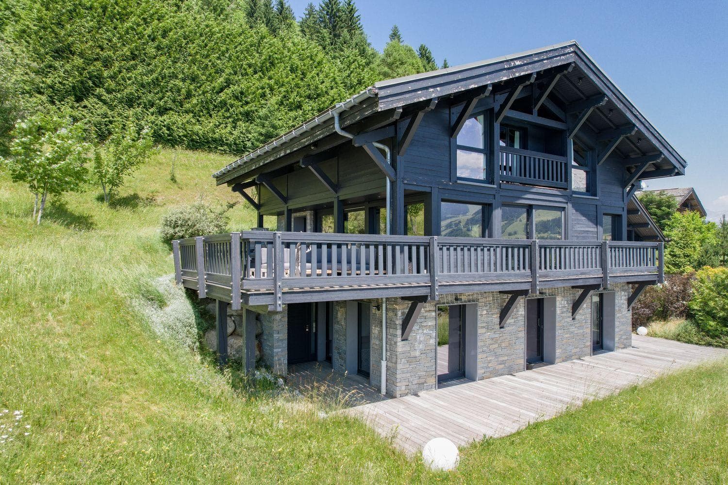 Chalet exterior featuring wrap-around deck and lower-level stone patio