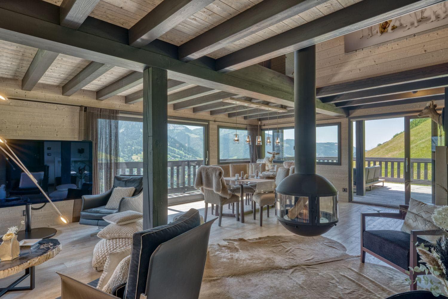 Open living area with suspended wood-burning fireplace and mountain-facing terrace access