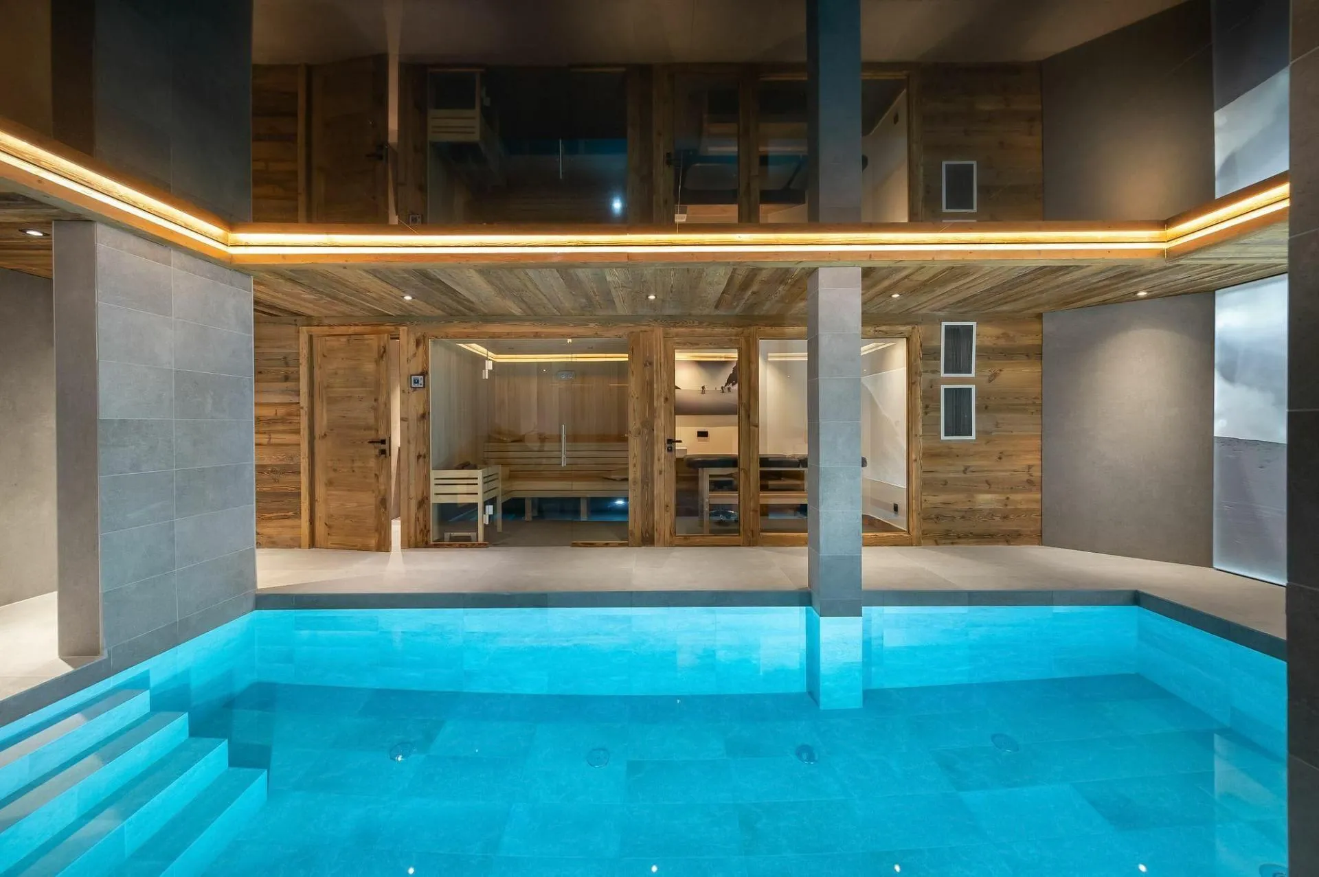 Indoor pool with steps and sauna beyond