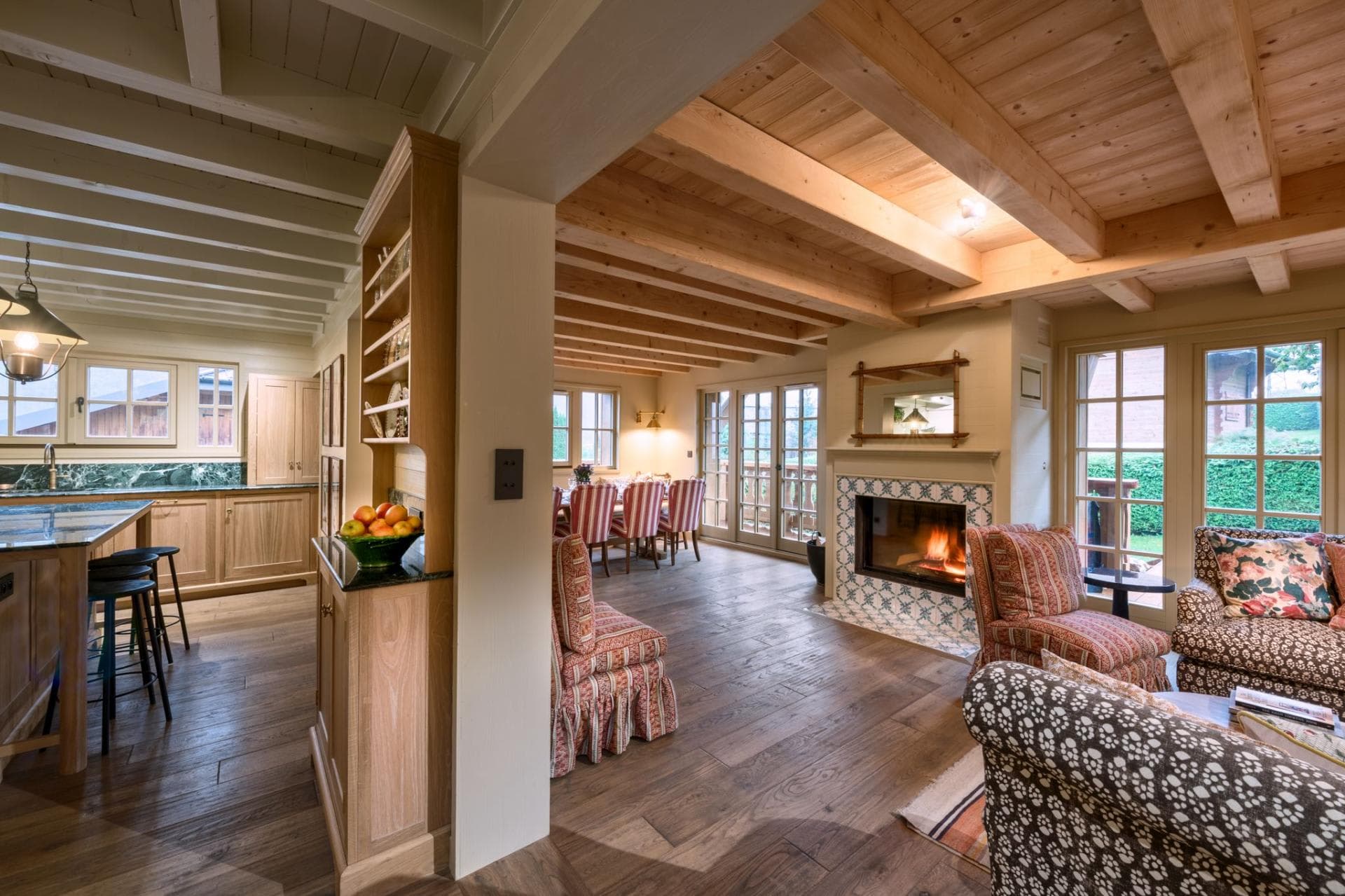 Open-plan living area featuring wood-burning fireplace and exposed timber ceilings