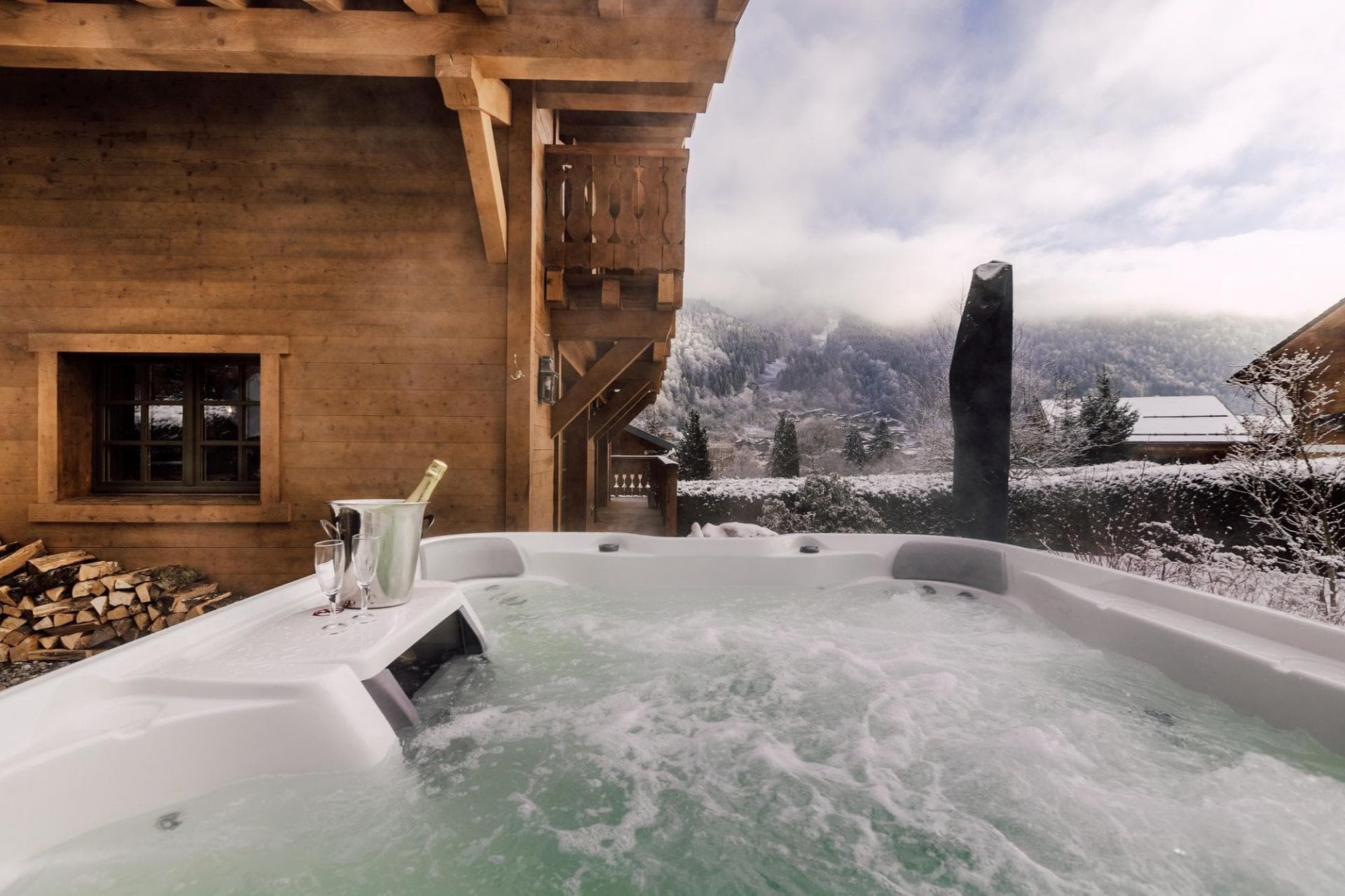 Outdoor hot tub with mountain views and adjacent wood storage