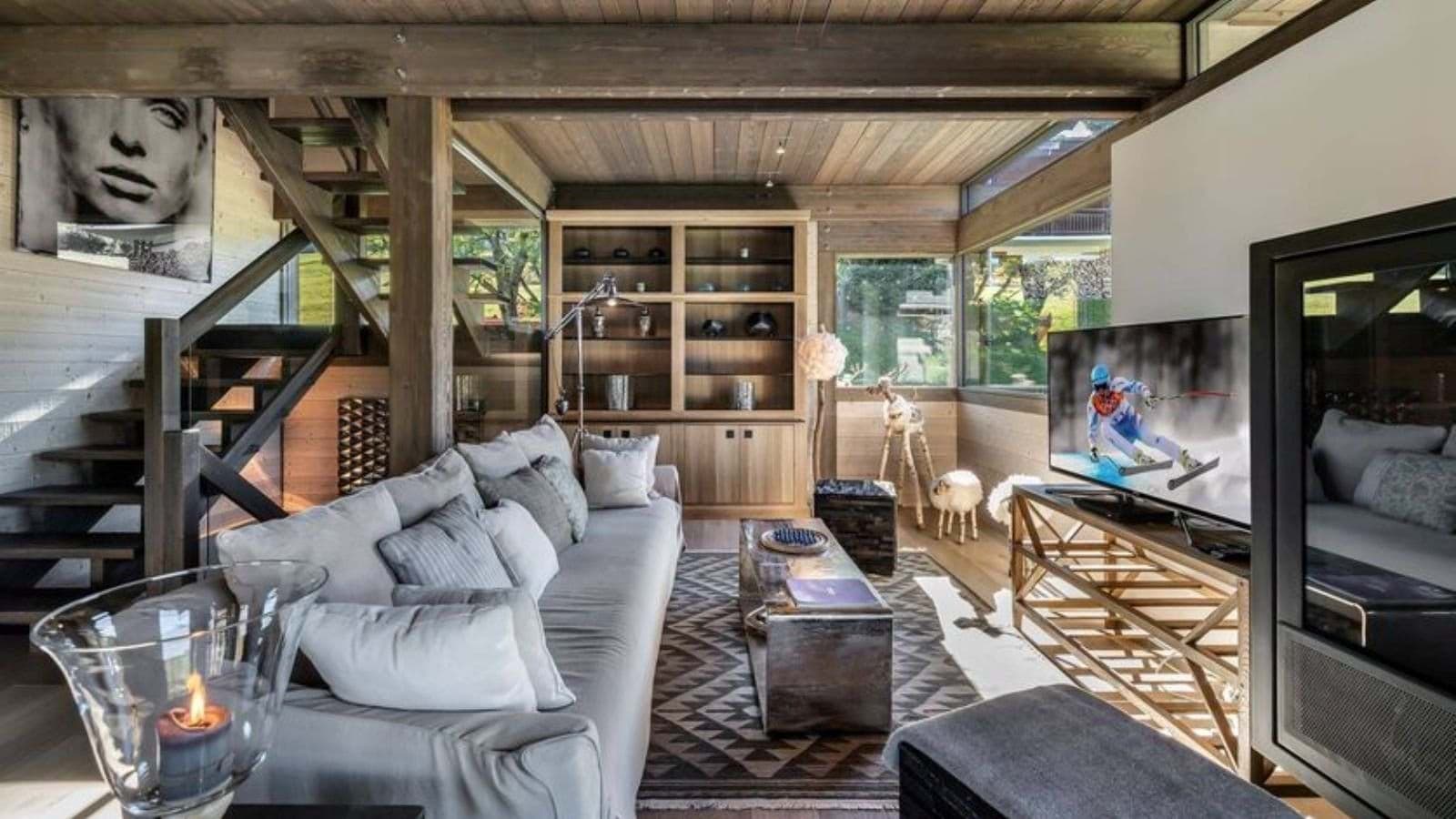 Living area with wood-beamed ceilings, smart TV, and open-tread staircase
