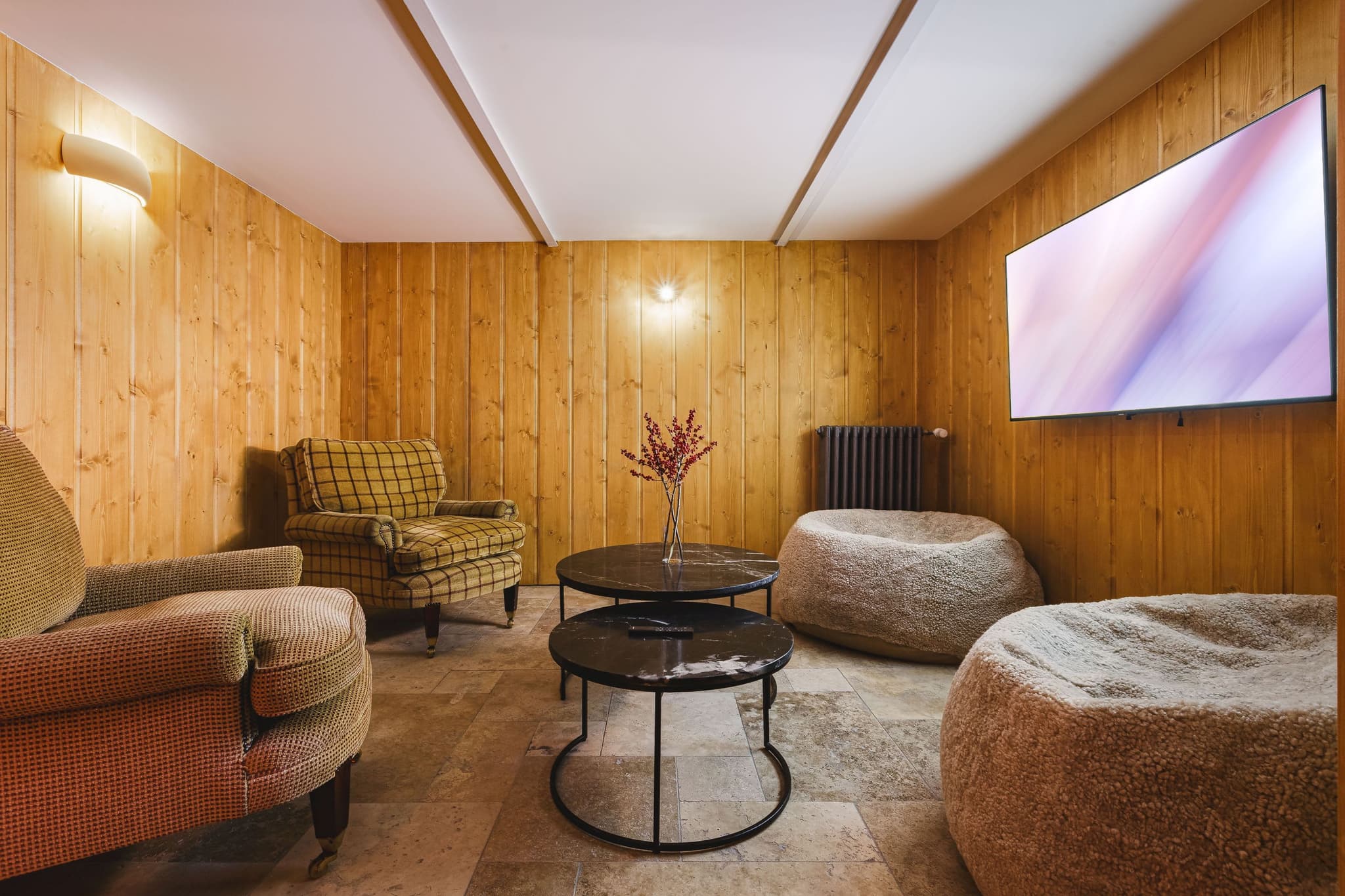 Media room with wood paneling, 65-inch smart TV, and bean bag seating