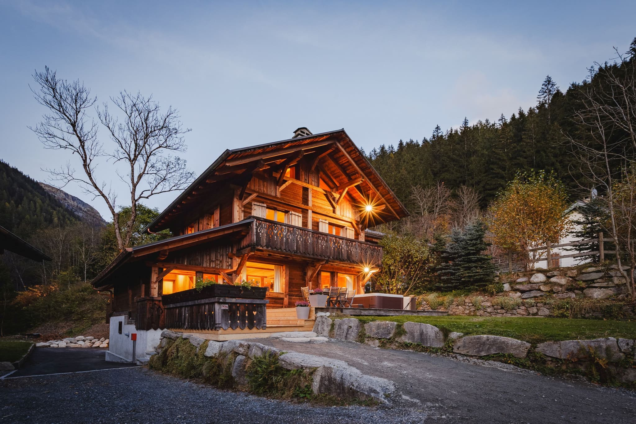 Timber chalet exterior with private terrace, hot tub, and forest backdrop