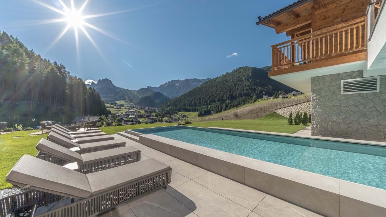 Outdoor lap pool and sun loungers with Dolomites mountain views