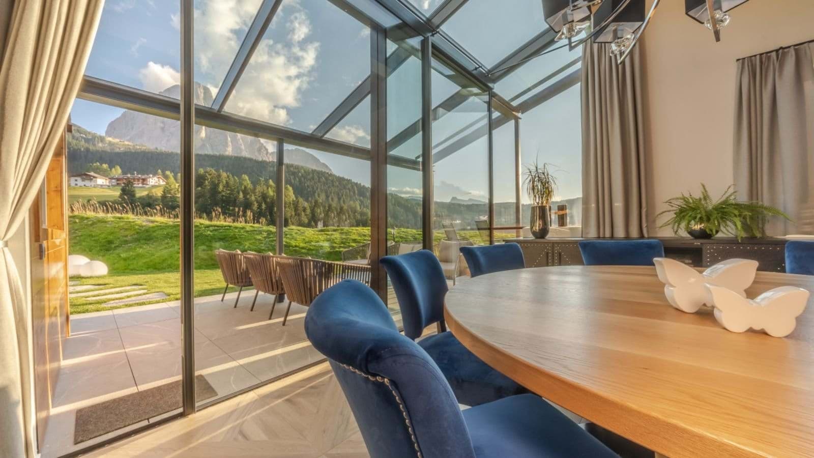 Dining area in glass sunroom with mountain views and patio access