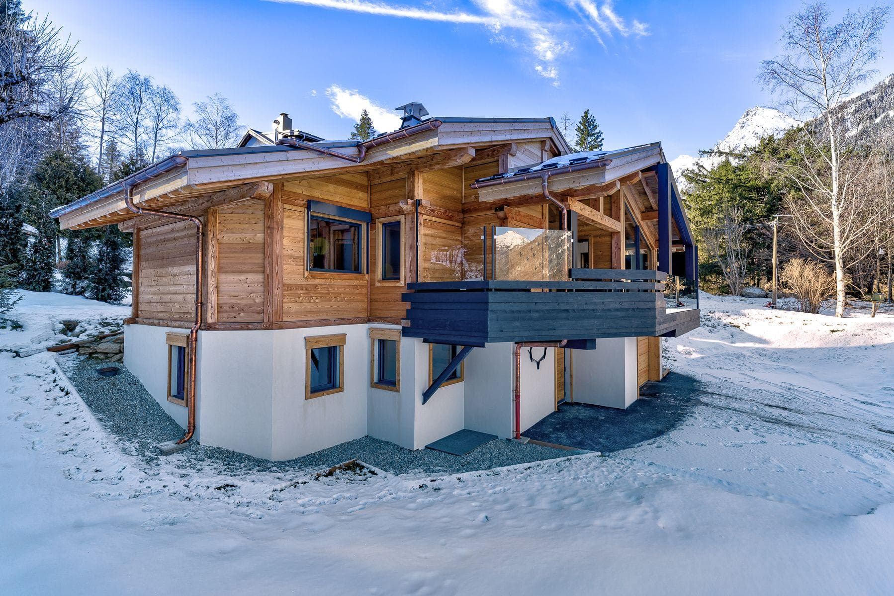 Ski chalet exterior with wrap-around glass balcony and mountain views