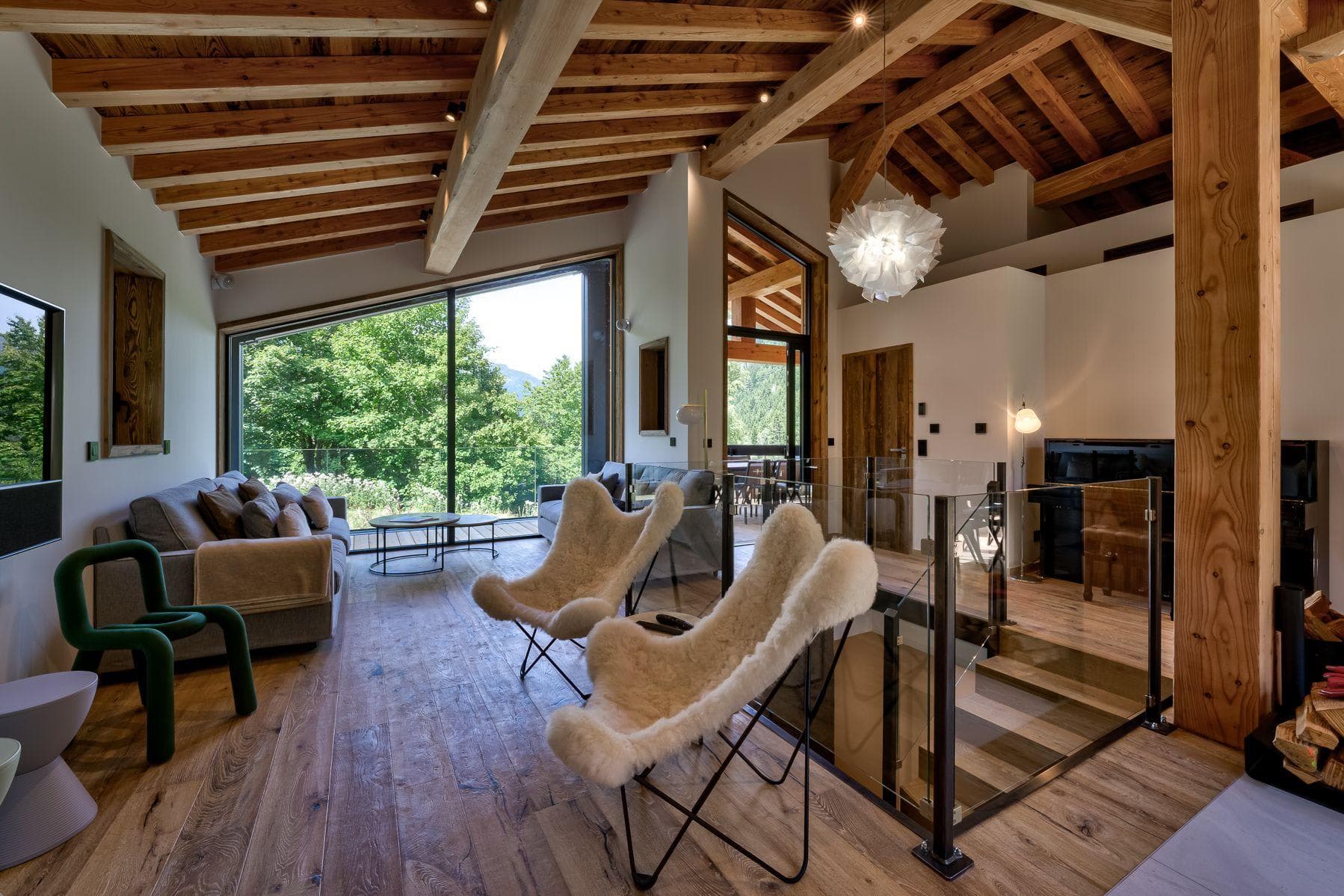 Upper-level living area with vaulted timber ceilings and forest views