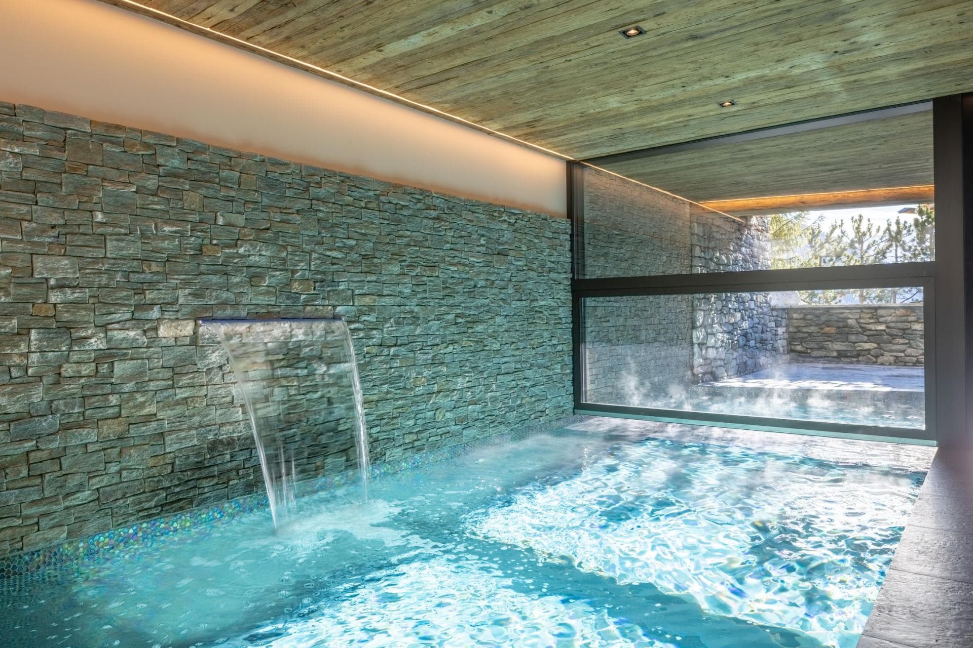 Heated indoor pool with waterfall feature and adjoining outdoor section