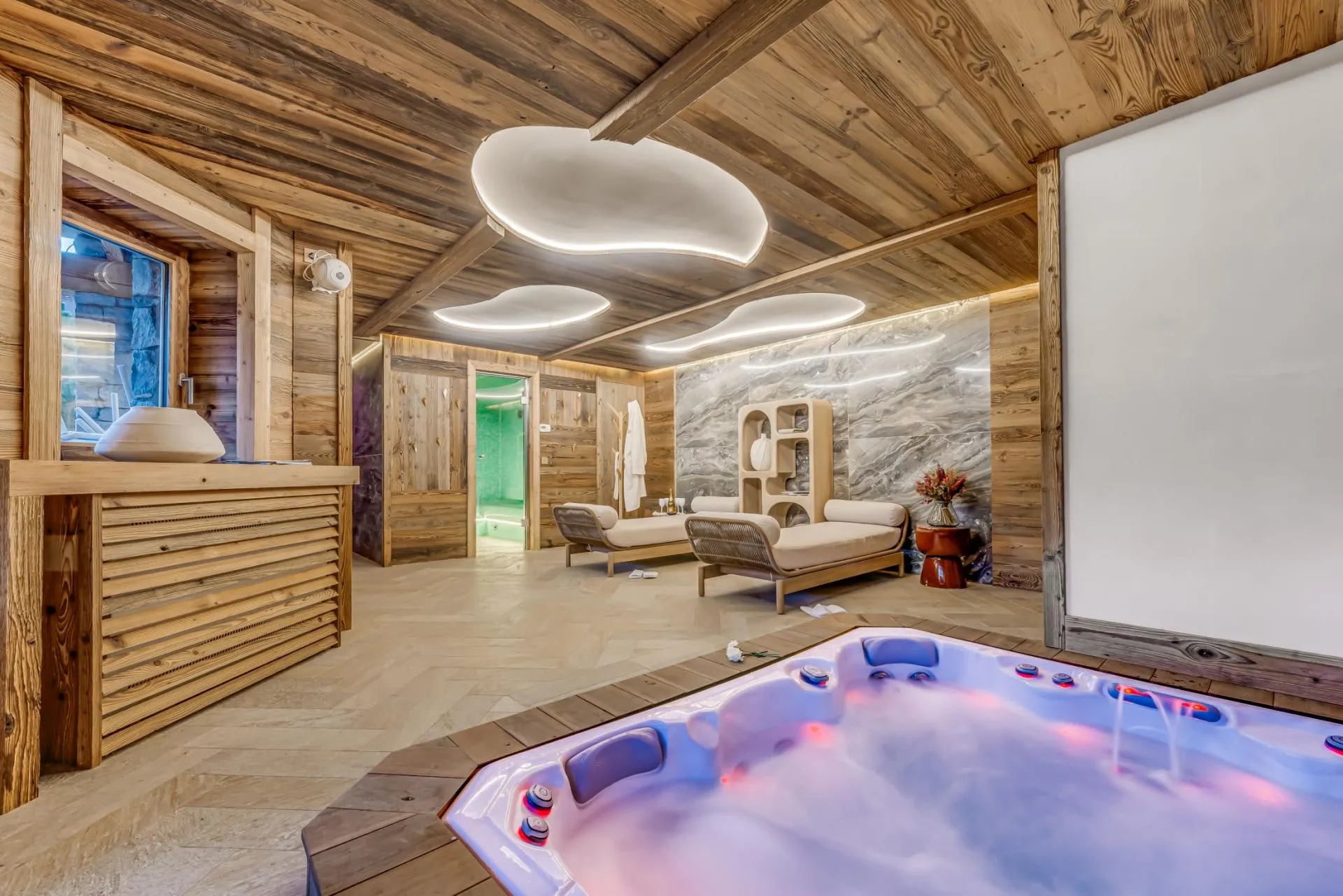 Spa area with indoor hot tub, loungers, and glass-enclosed steam room