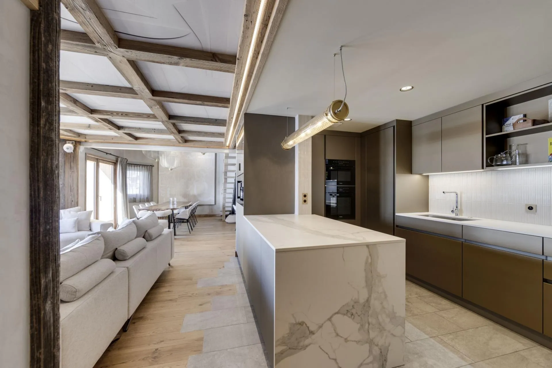 Kitchen with marble island and integrated appliances; exposed beam ceiling