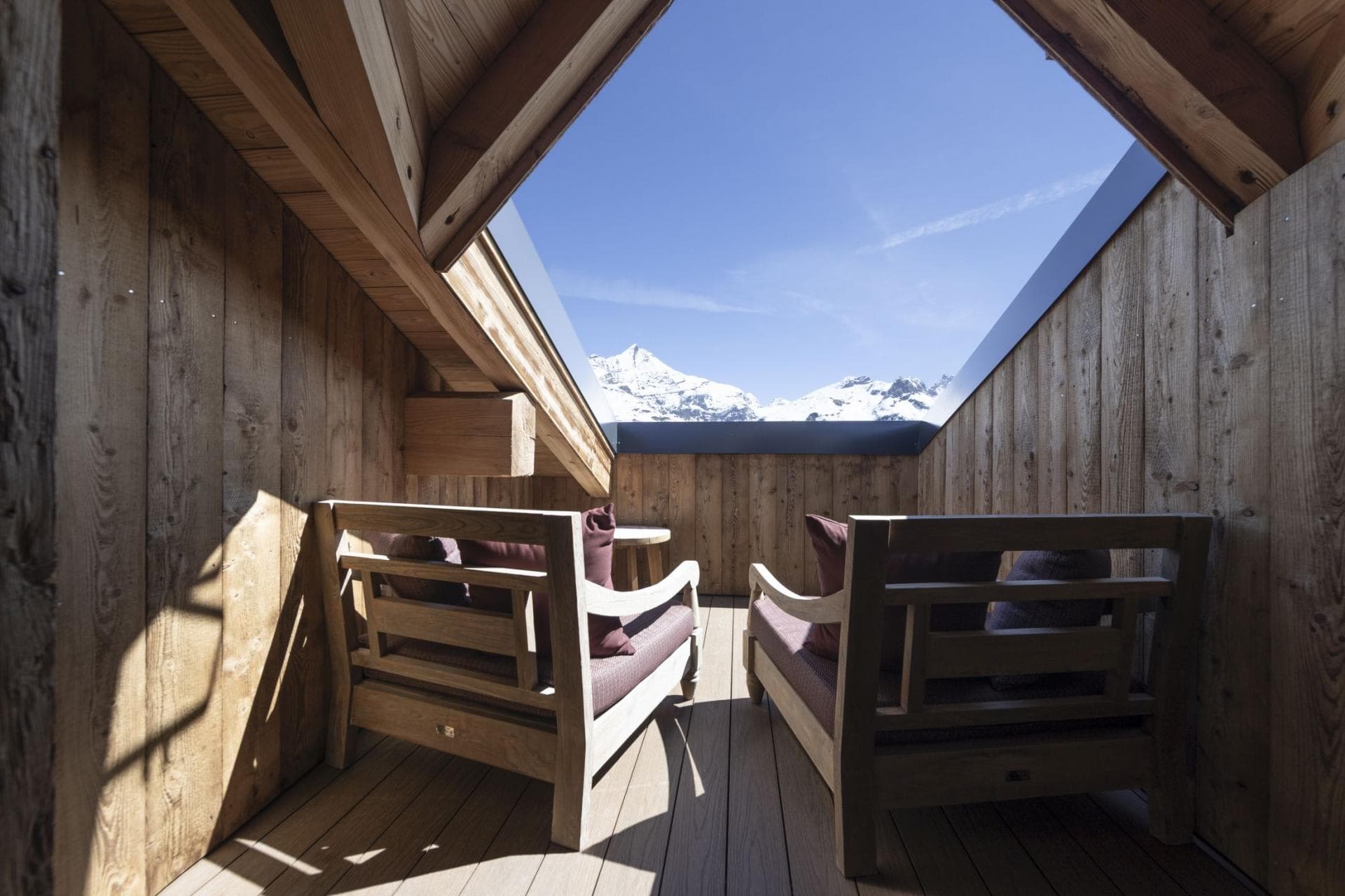 Private wood-paneled balcony with seating for two and mountain views