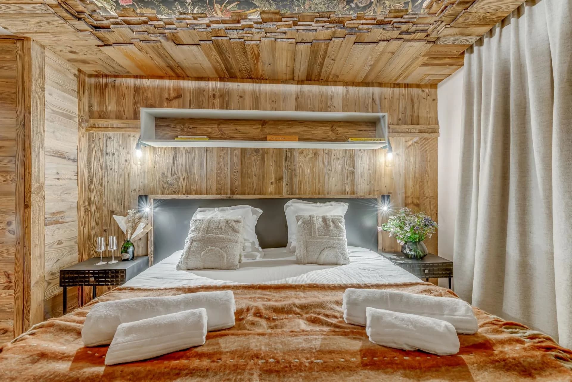 Wood-paneled bedroom with king bed and integrated reading lights