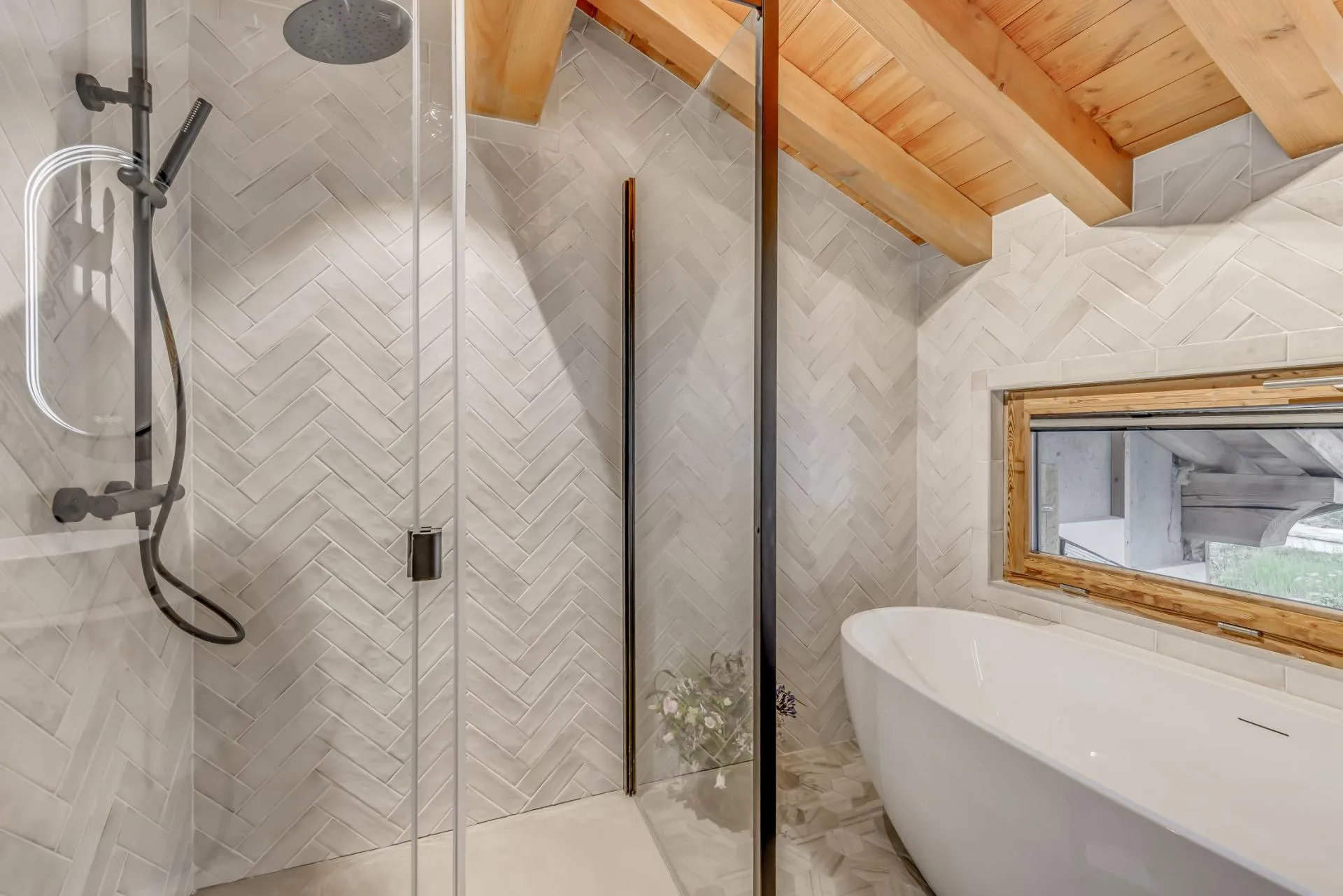 Walk-in rain shower and freestanding tub under vaulted wood ceilings