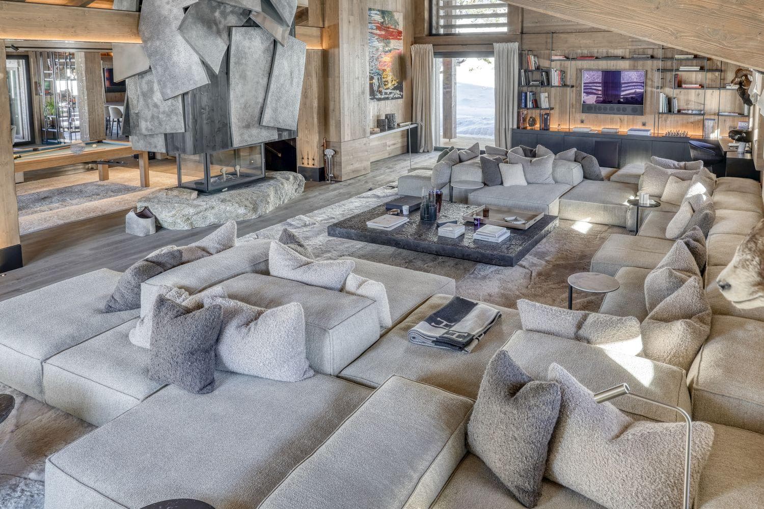 Living area with sculptural fireplace, modular sectional seating, and pool table