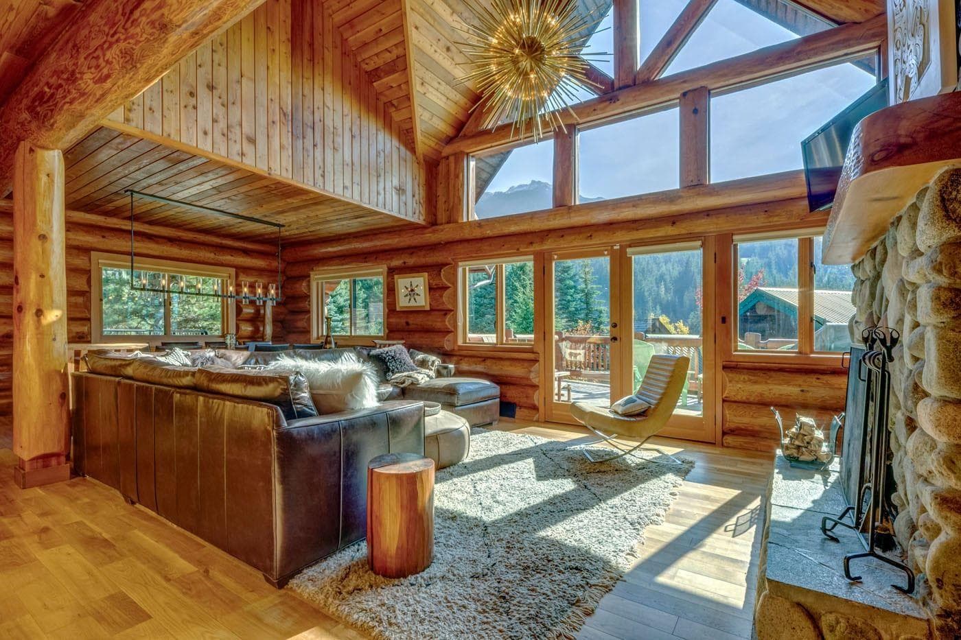 Living room with leather sectional, stone fireplace, and mountain views