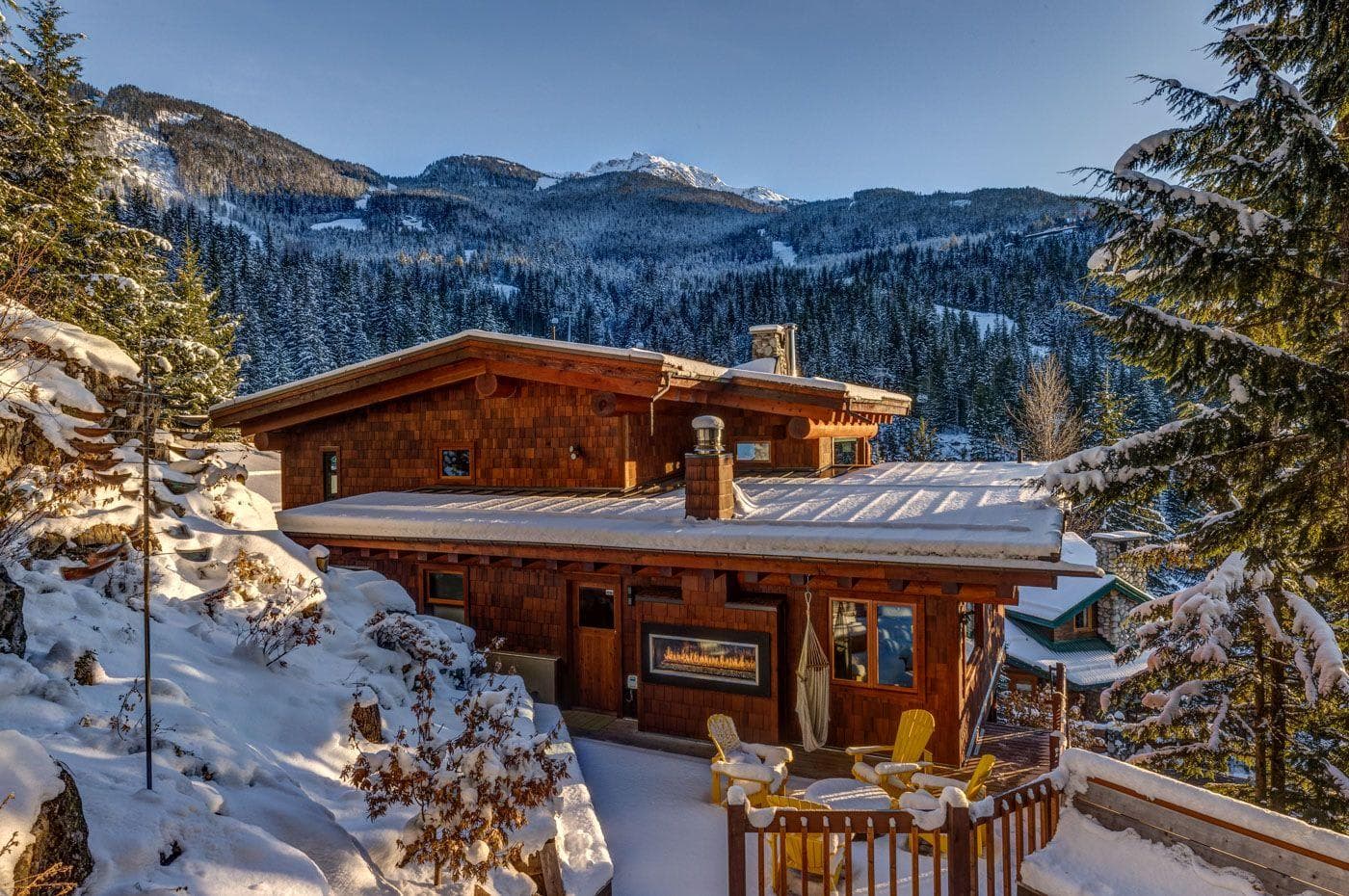 Cabin exterior with outdoor fireplace, patio seating, and mountain views
