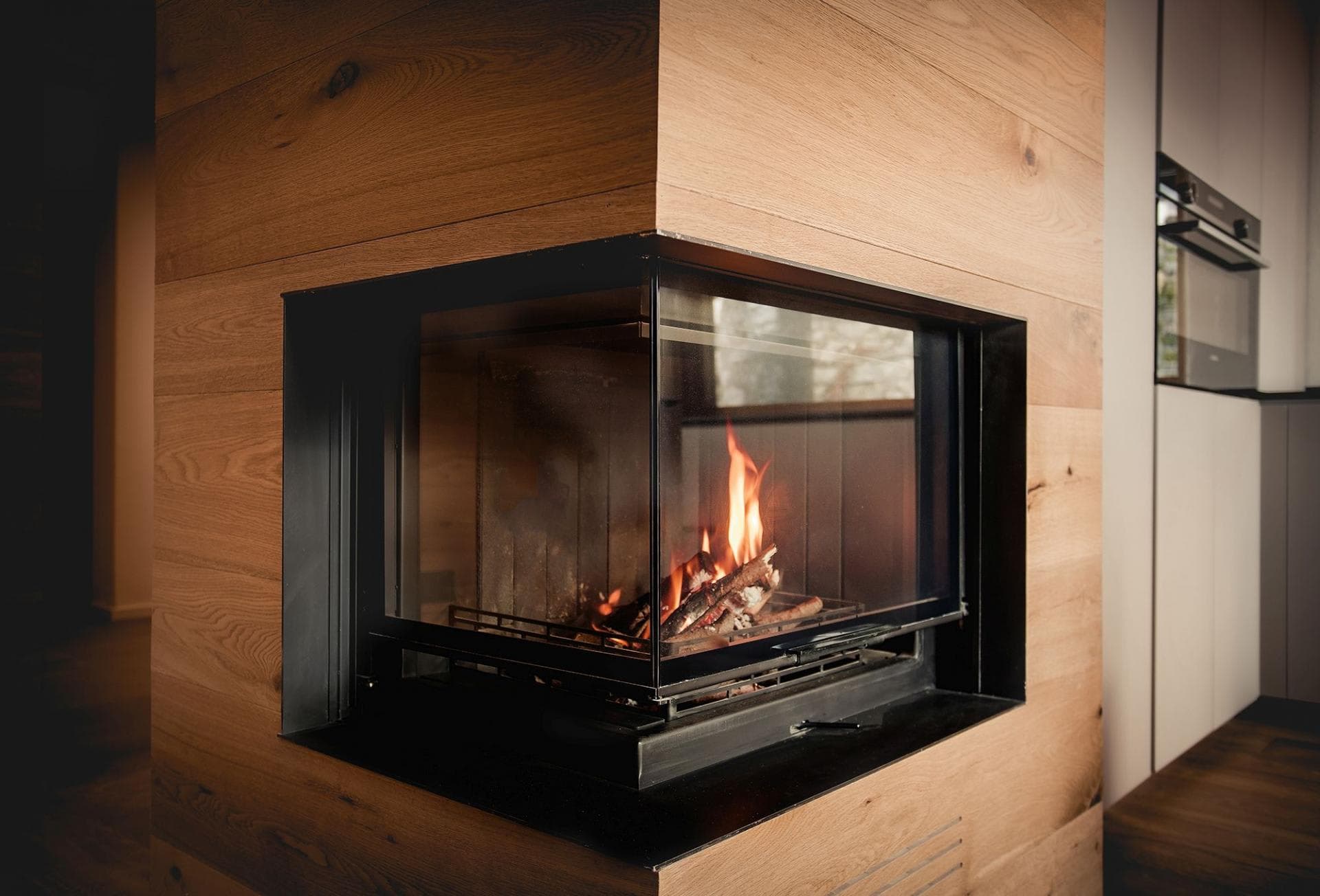 Double-sided glass wood fireplace between living area and kitchen