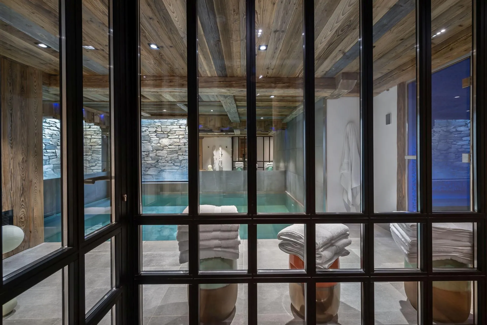 Indoor pool and relaxation seating behind glass partition