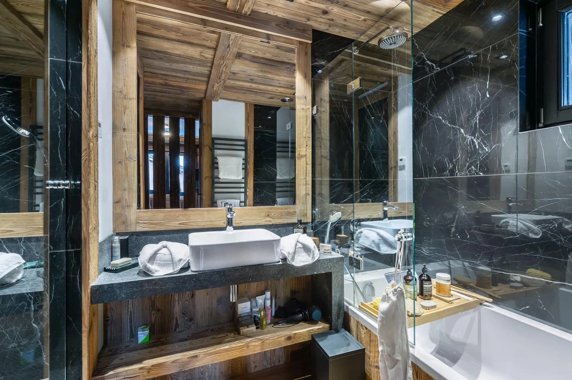 Bathroom with bathtub, basin vanity and dark stone walls