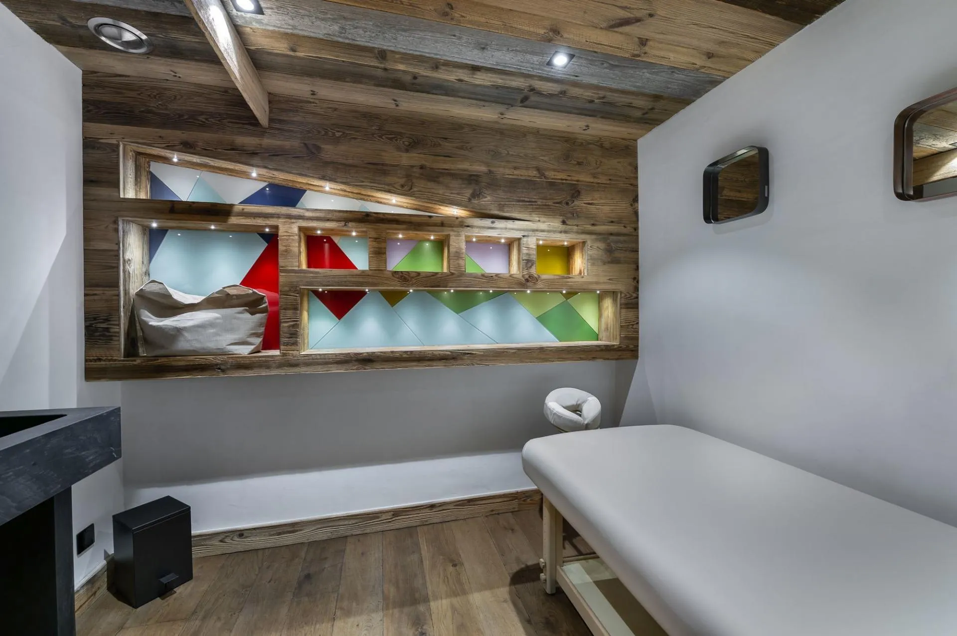 Treatment room with massage table and coloured shelving