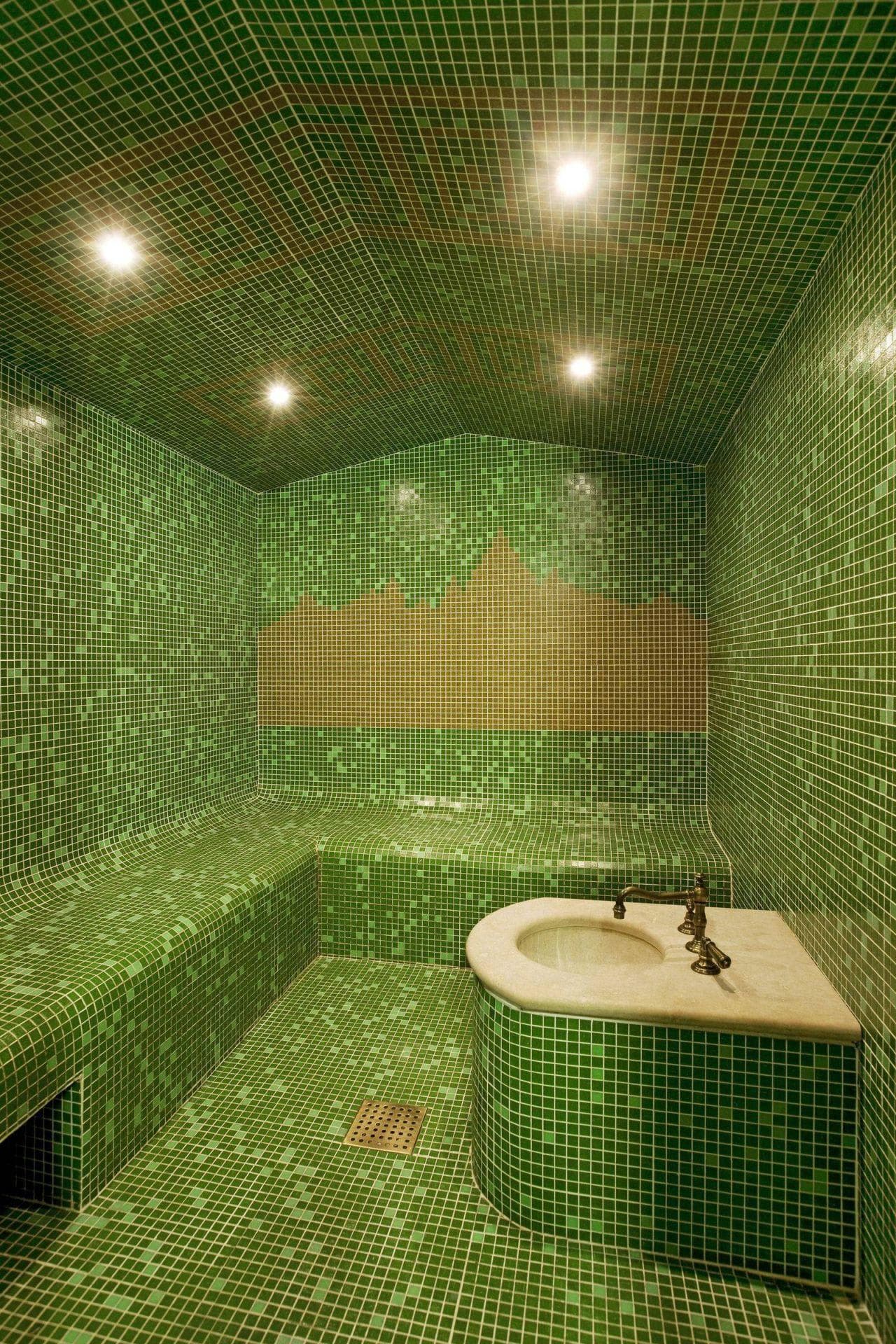 Mosaic steam room with heated bench seating and integrated marble sink