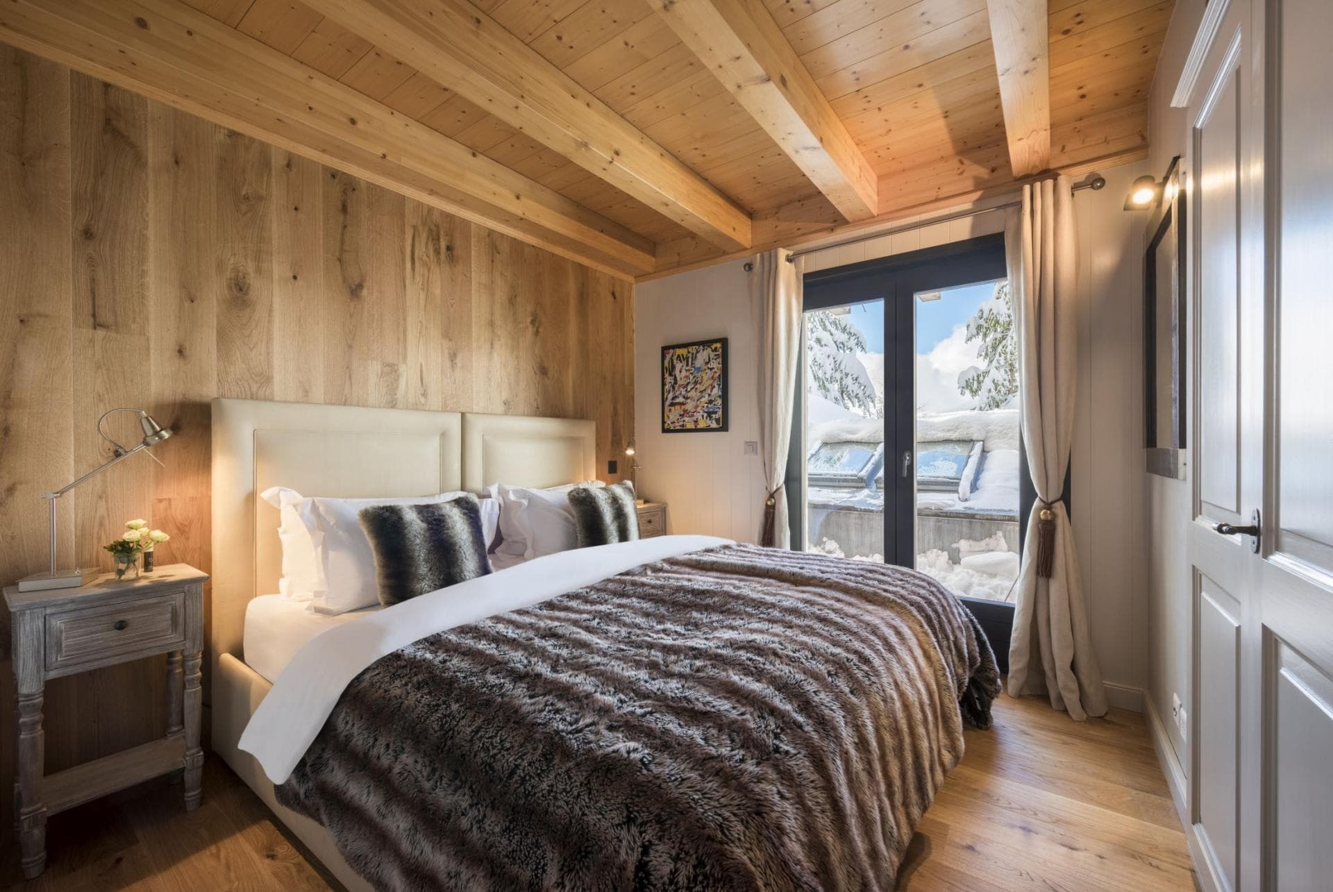 Guest bedroom with king bed and terrace access to snowy views
