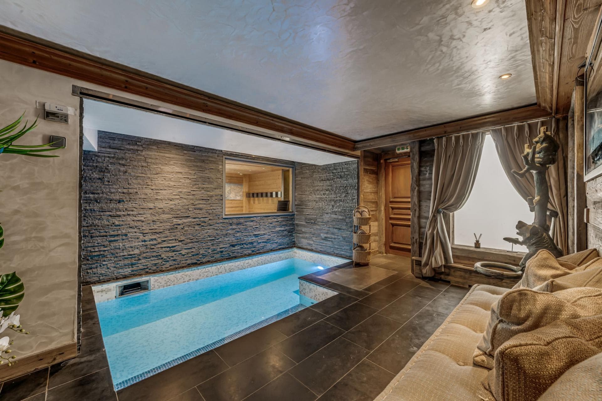 Indoor heated pool and lounge area with adjacent wood-paneled sauna