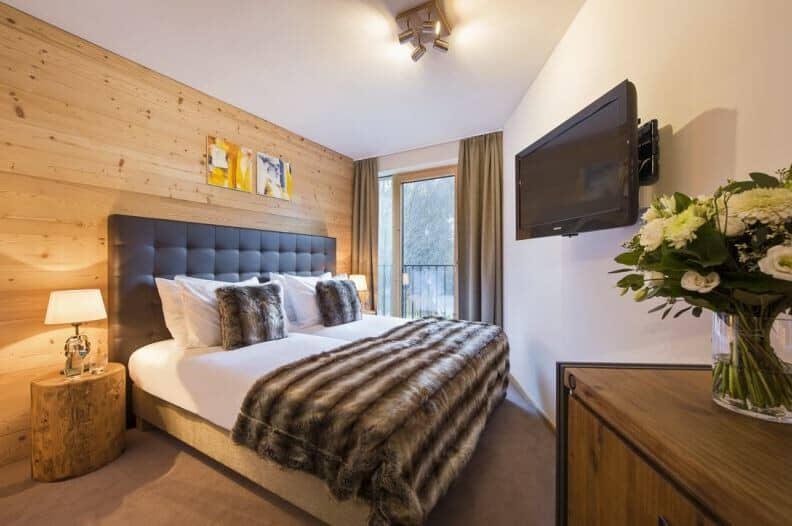 Bedroom with king bed, wall-mounted TV, and balcony access