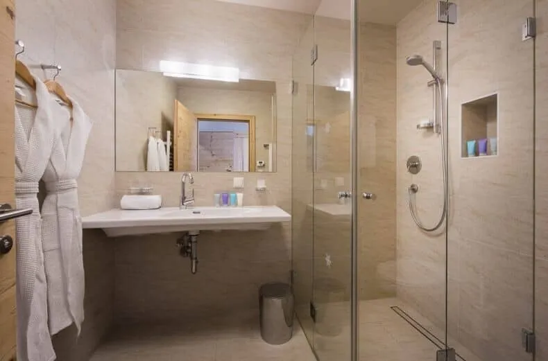 Bathroom with walk-in glass shower, handheld head, and wall-mounted vanity