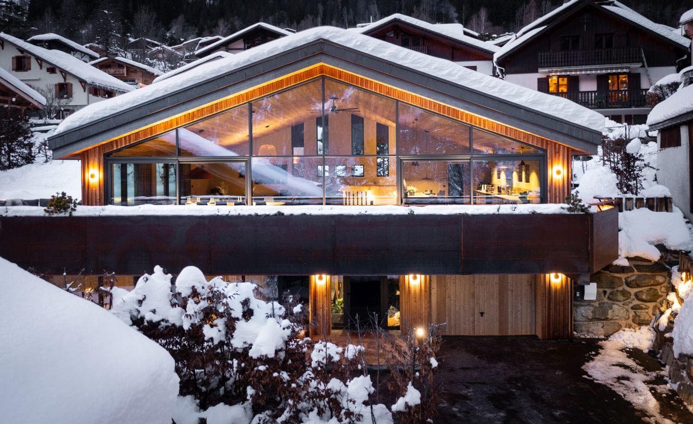 Chalet exterior featuring floor-to-ceiling windows and heated driveway with garage