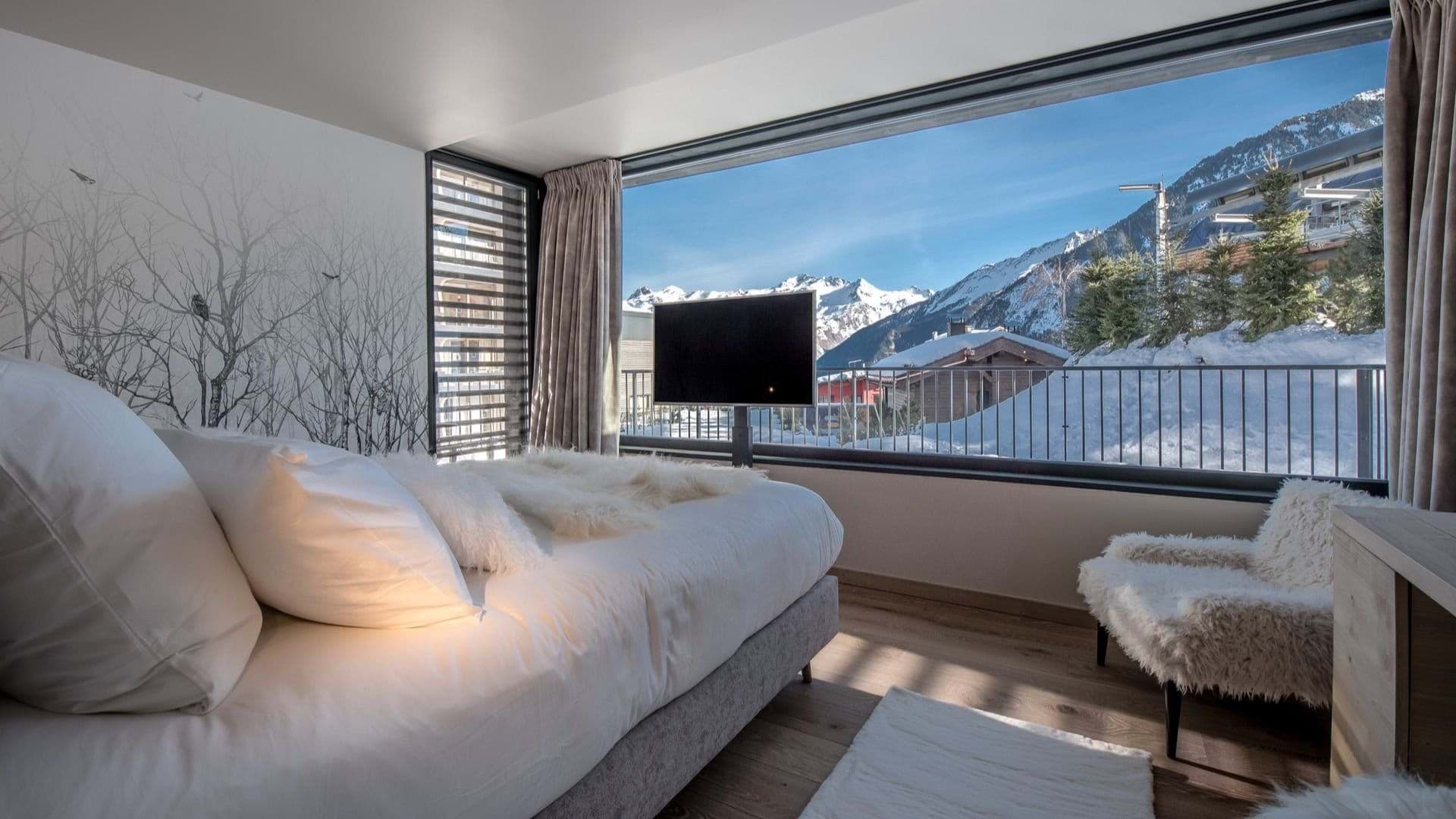 Bedroom with king bed and floor-to-ceiling snowy mountain views