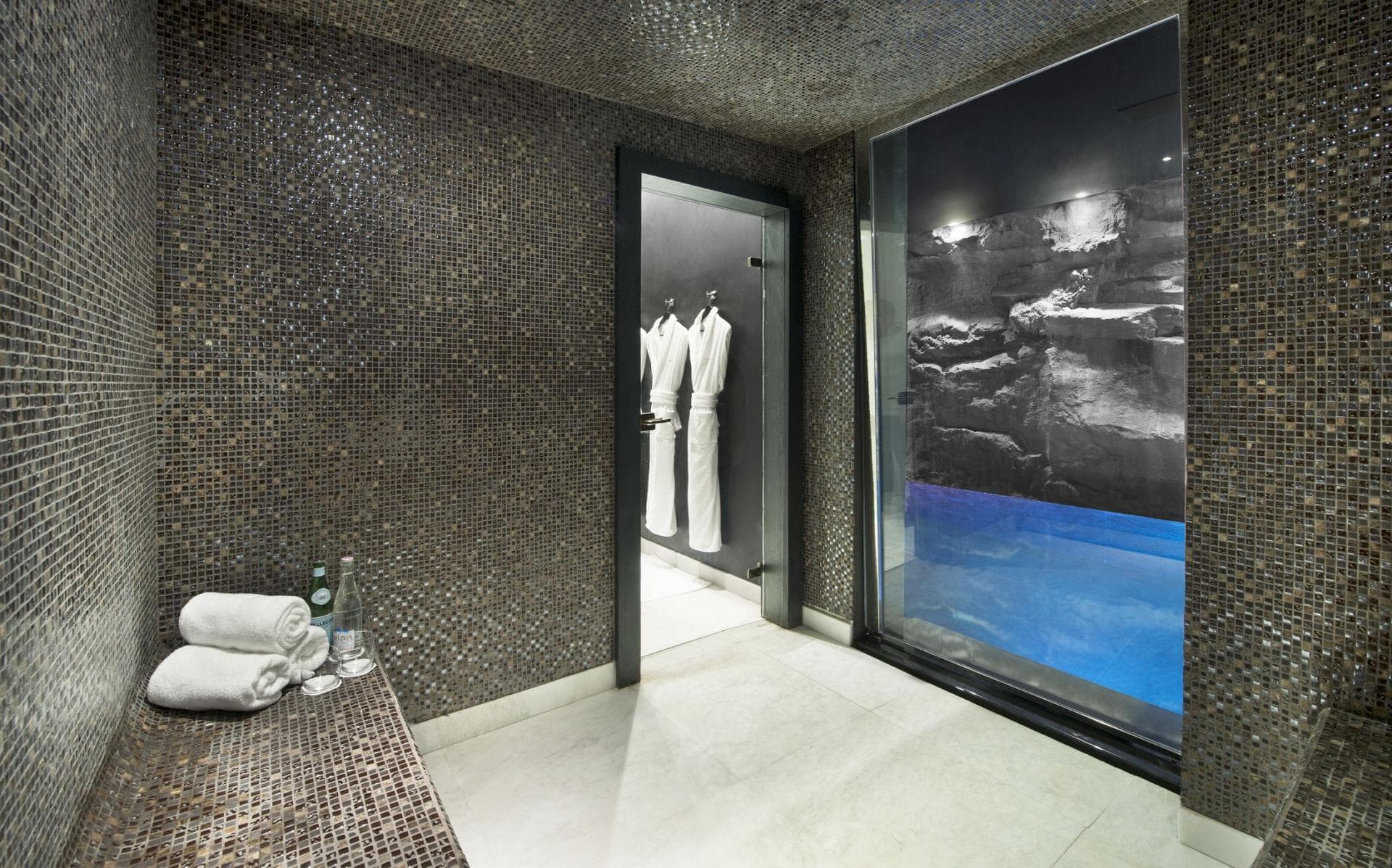 Private steam room with mosaic tile and window overlooking the indoor pool