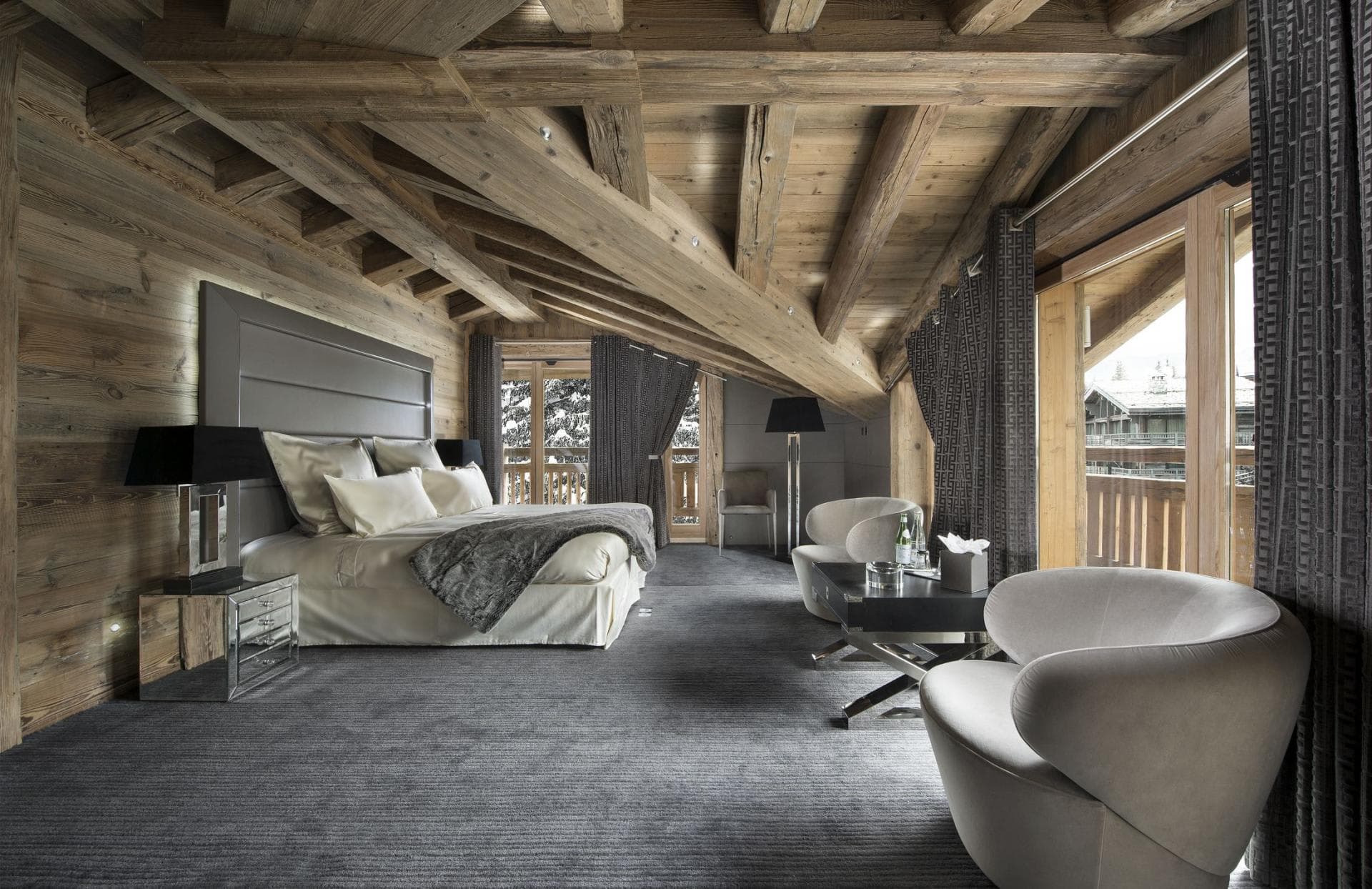 Top-floor primary suite with king bed, vaulted timber ceilings, and balcony access