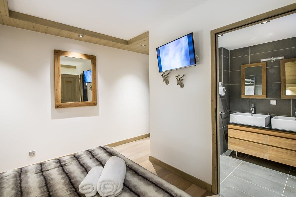 Guest bedroom with wall-mounted TV and ensuite bathroom with dual vanity