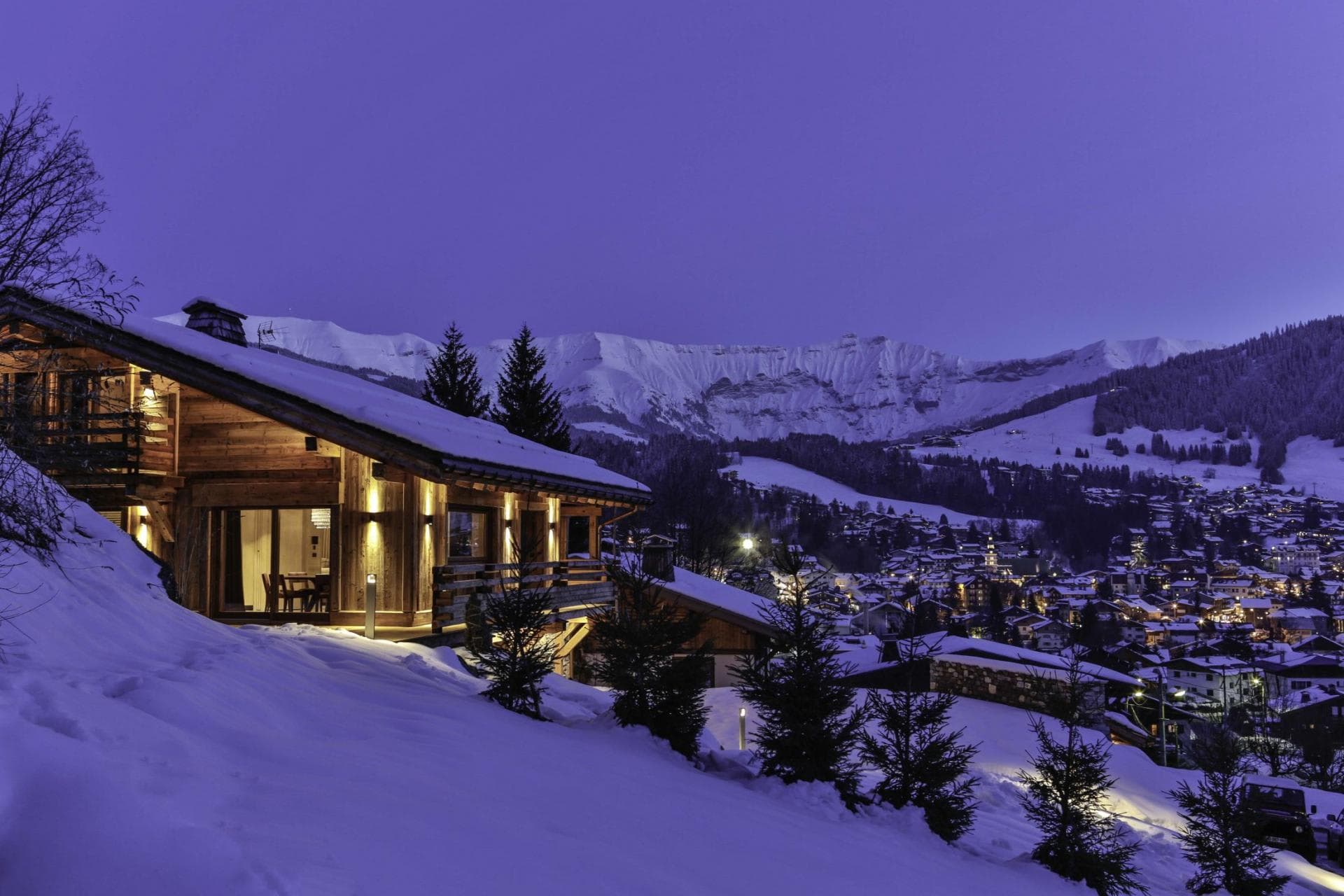 Ski chalet exterior with village and mountain range views at dusk