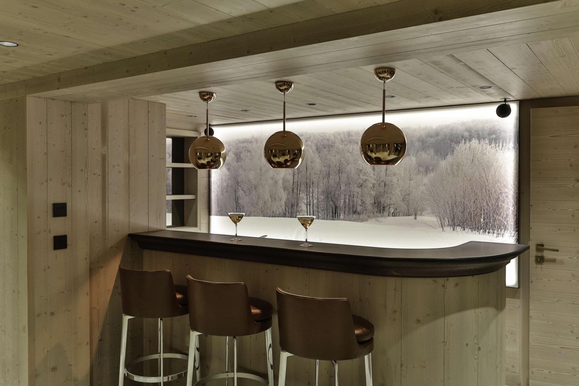 Lower-level wet bar with leather seating and illuminated forest mural