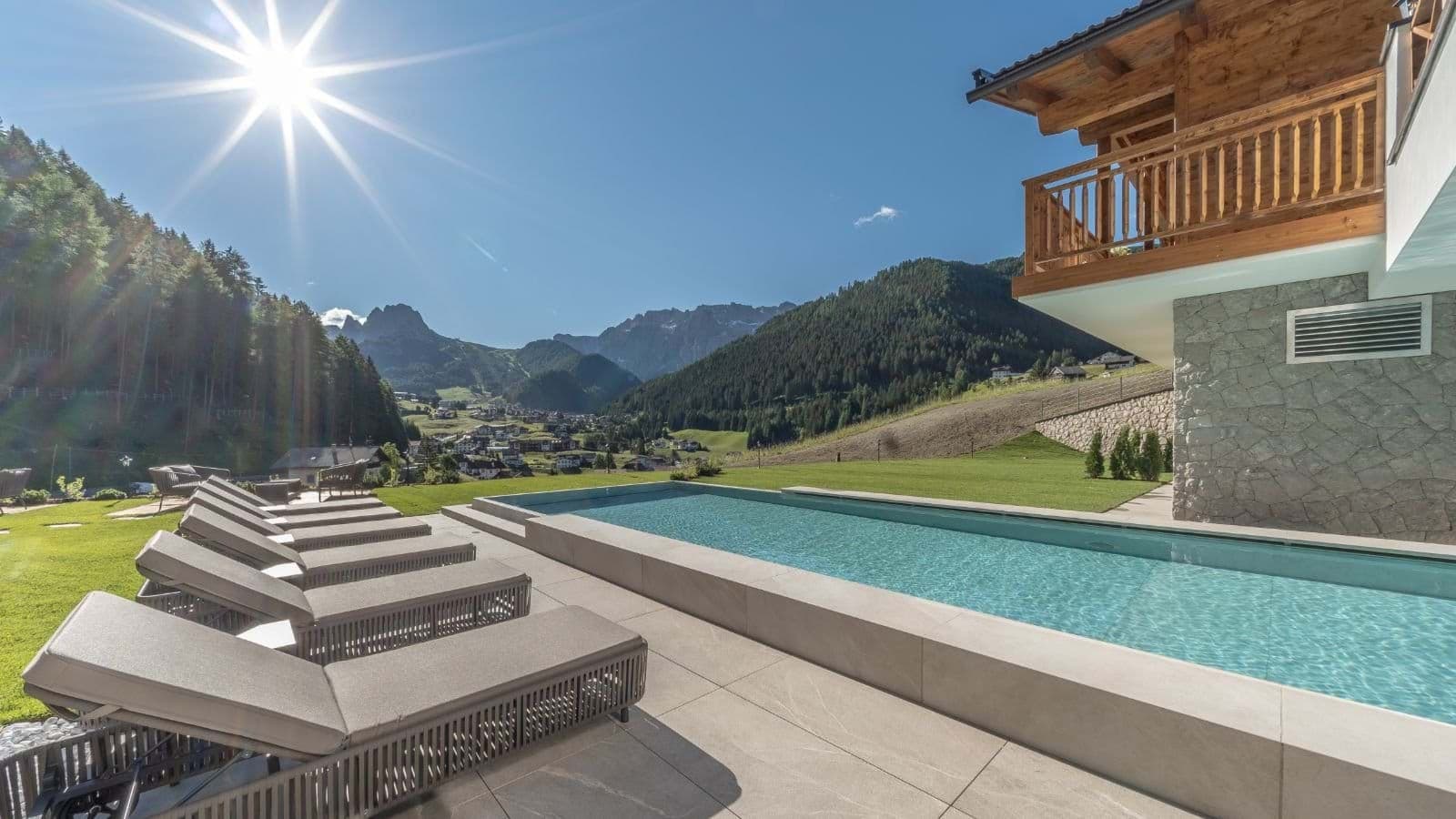 Outdoor lap pool with lounge seating and Dolomites mountain views