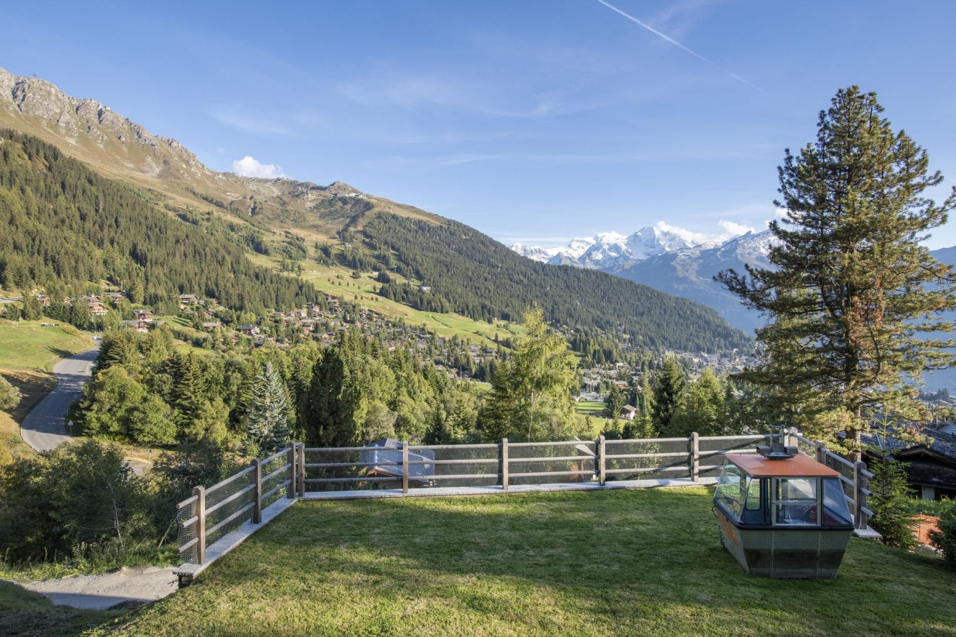 Fenced lawn with repurposed gondola cabin and panoramic valley views
