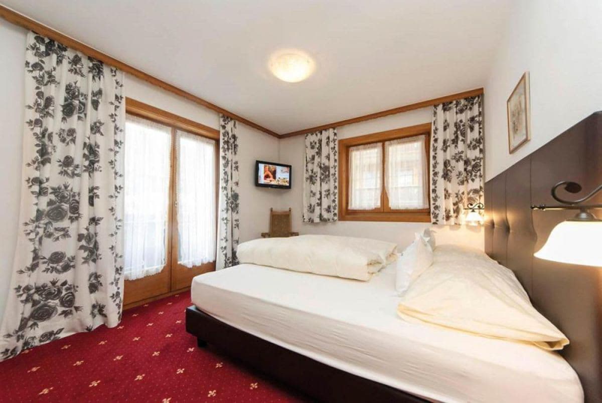 Guest bedroom with king bed, wall-mounted TV, and balcony access
