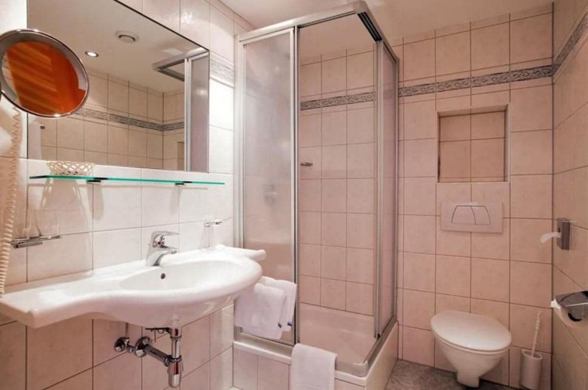 Bathroom with walk-in shower, wall-mounted toilet, and magnifying vanity mirror