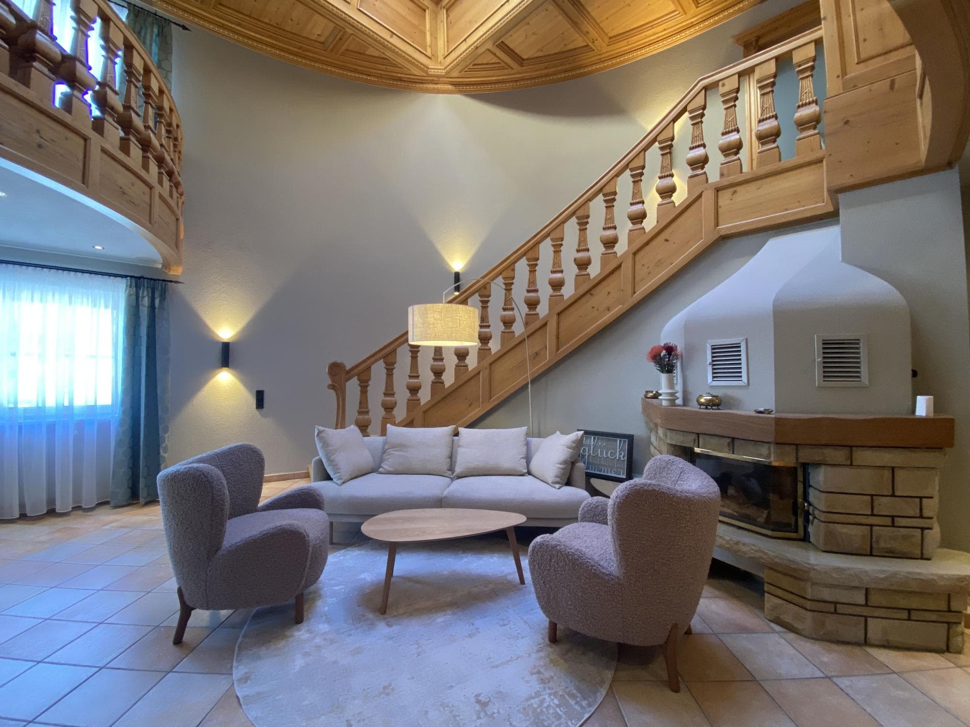 Living area with wood-burning fireplace and ornate timber staircase
