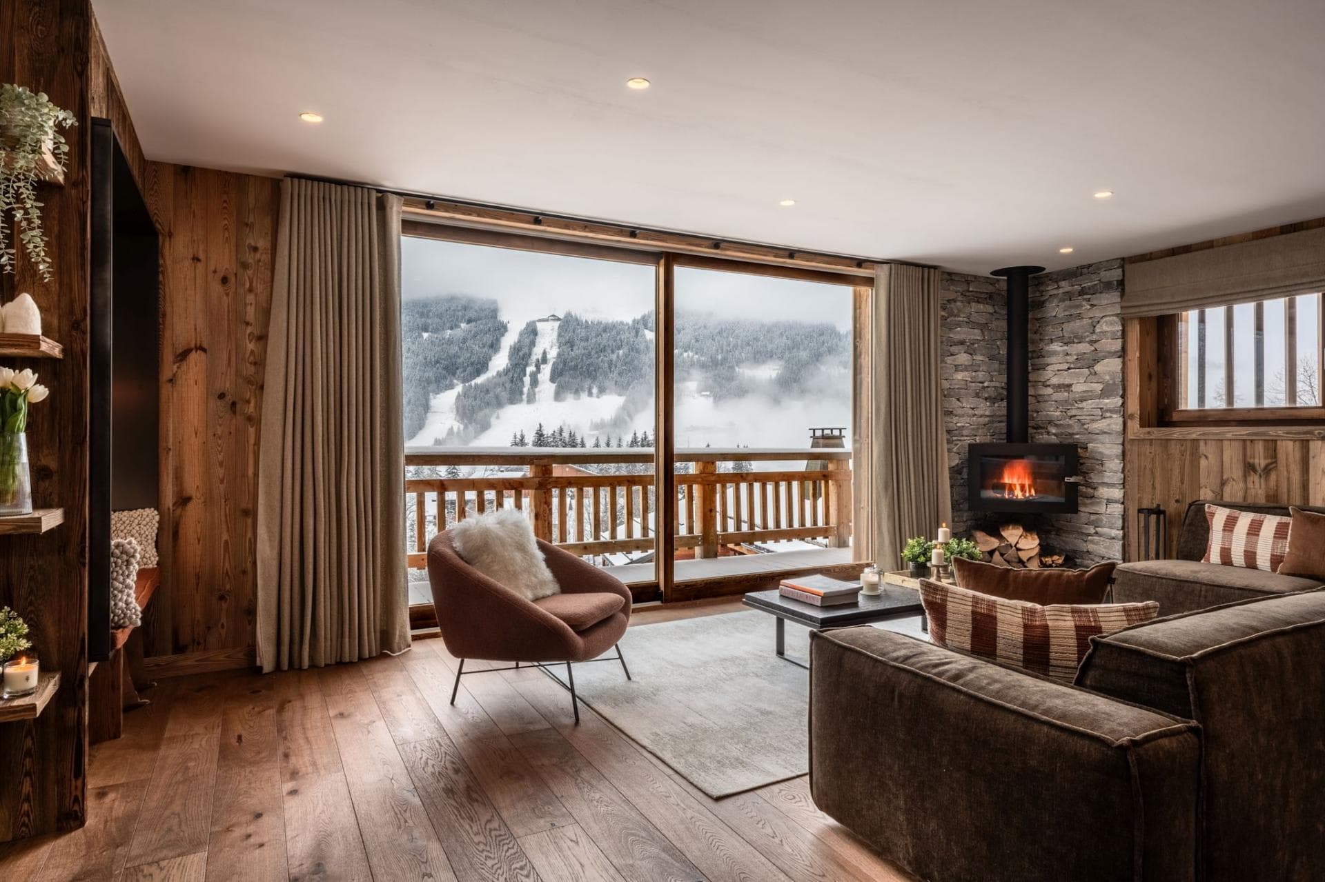 Living area with wood-burning stove and floor-to-ceiling ski slope views