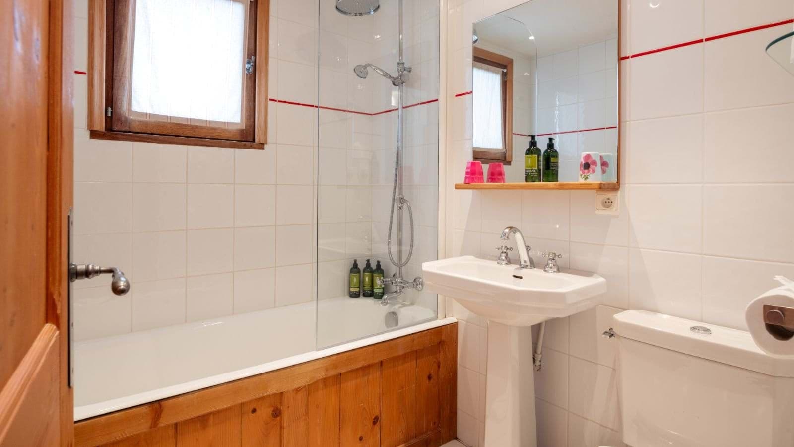 Bathroom featuring soaking tub with shower wand and glass partition