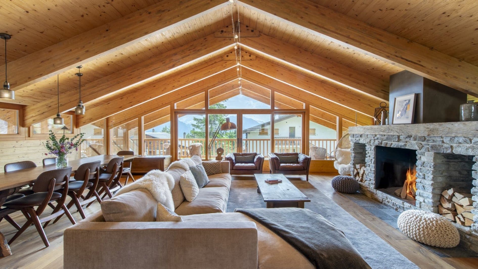 Living area with wood-burning stone fireplace and floor-to-ceiling mountain views