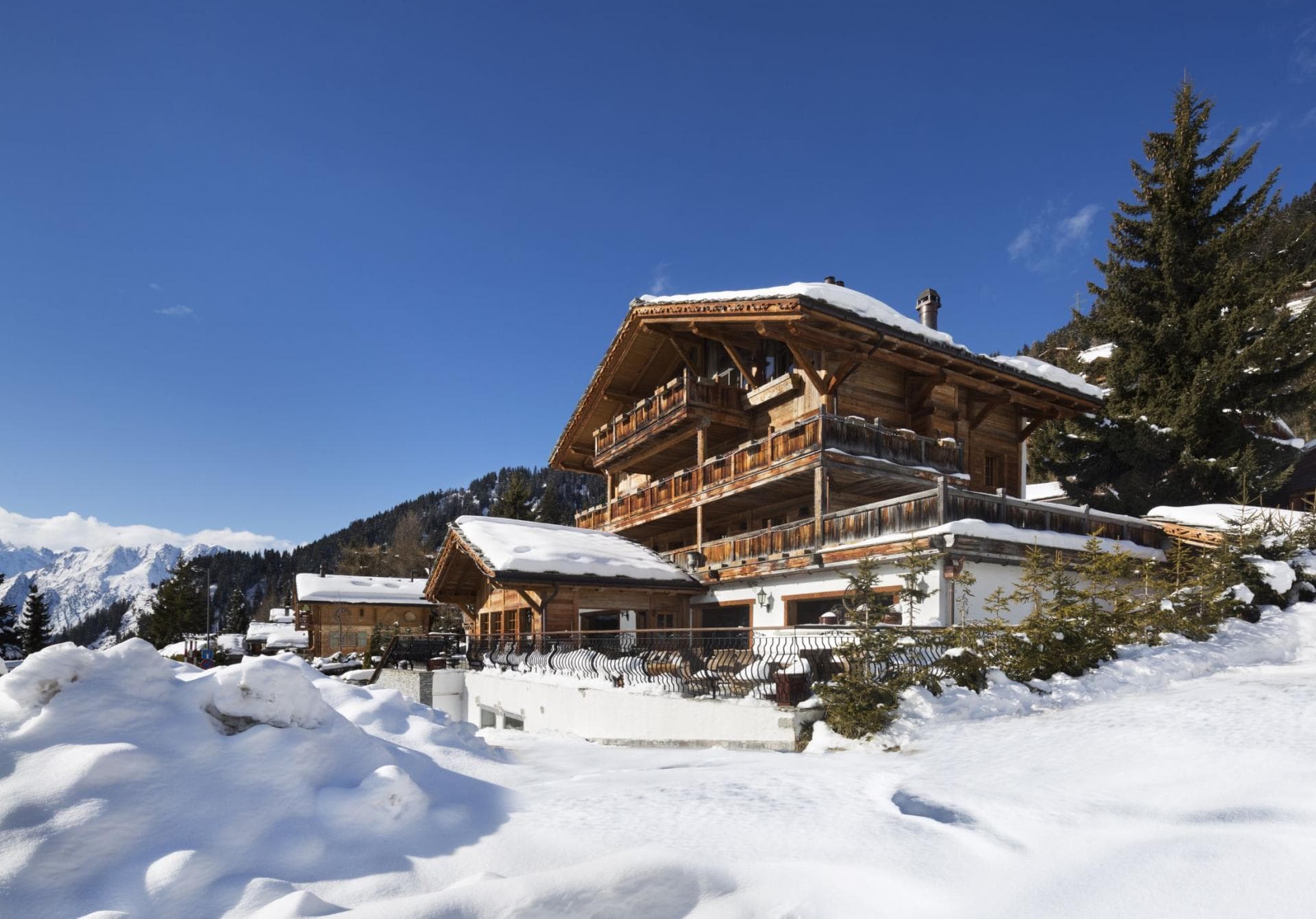 Chalet exterior with multi-level wooden balconies and snowy mountain views