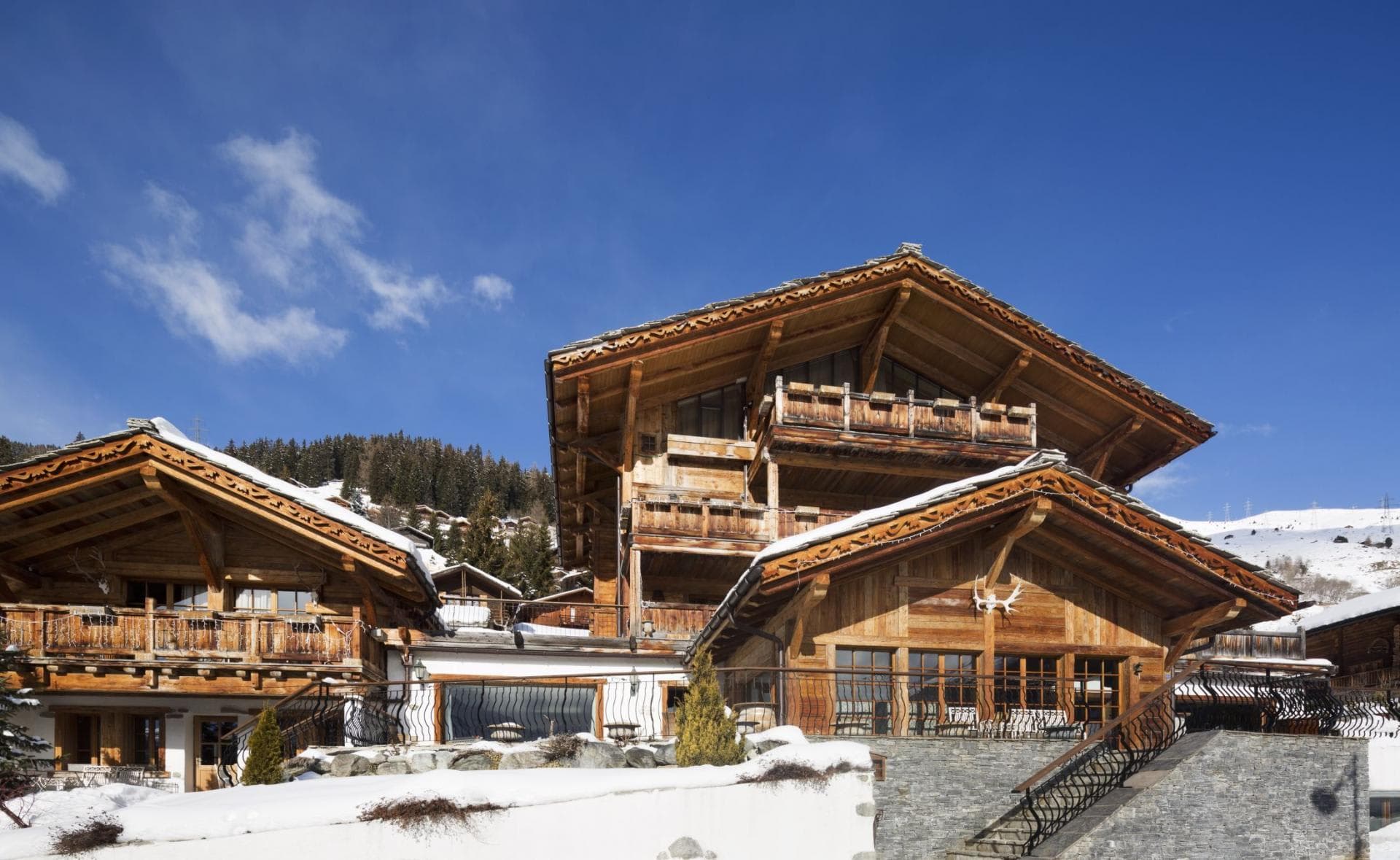 Timber chalet exterior with multi-level balconies and large stone terrace