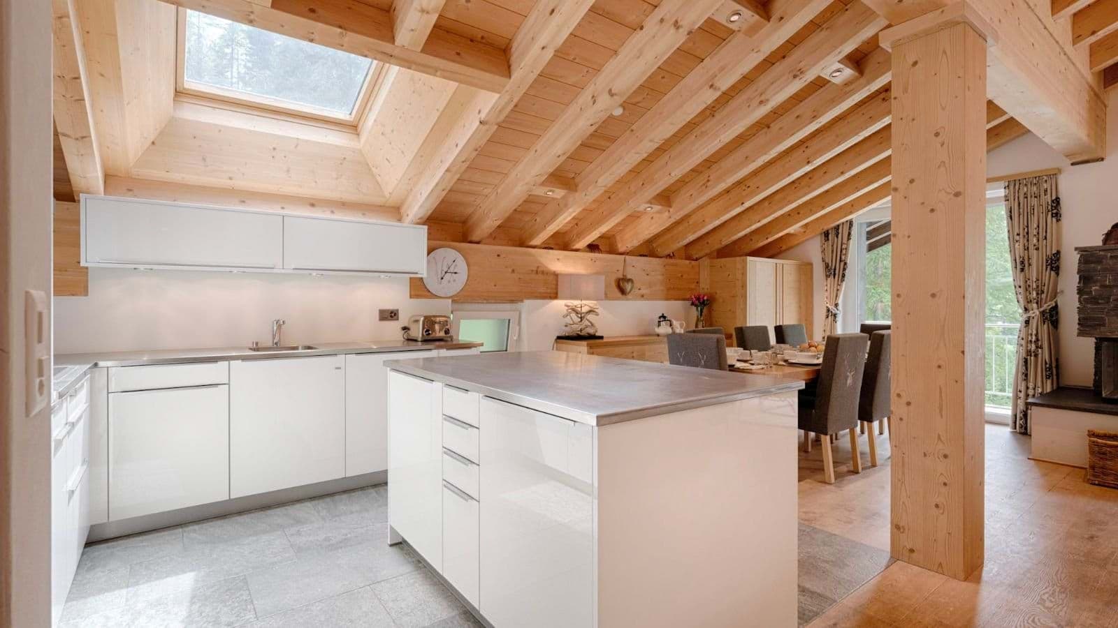 Open-plan kitchen and dining area with skylight and wood-beamed ceilings