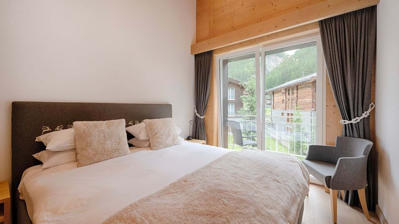 Guest bedroom with balcony access and wood-paneled ceiling detail