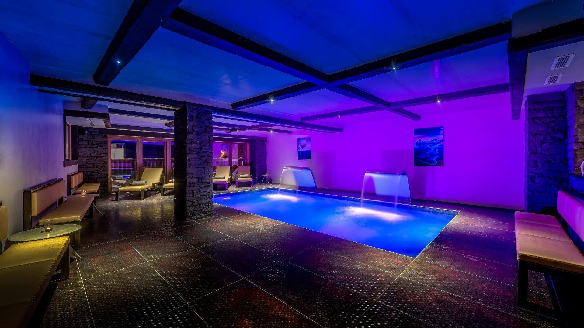 Indoor pool with waterfall features and poolside bench seating